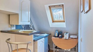 Een kleine keuken met een eethoek, een raam met uitzicht op de stad en een compacte koelkast.