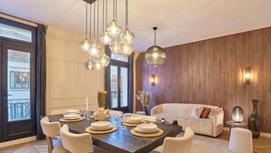A dining area with a large table set for six, surrounded by chairs. There is a sofa and a decorative vase in the background. - Superb Apartment Terrace Champs Elysees (Paris)