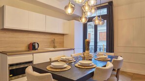 A modern kitchen with a central island, stainless steel appliances, and a dining area with a dark wooden table set for four. - Superb Apartment Terrace Champs Elysees (Paris)