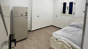 Ein Schlafzimmer mit einem Bett, einem Kleiderschrank und einem Kühlschrank.