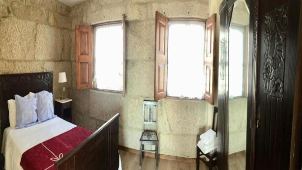Ein Schlafzimmer mit einem Bett, einem Nachttisch, einem Sessel, einem kleinen Tisch und einer Tür.