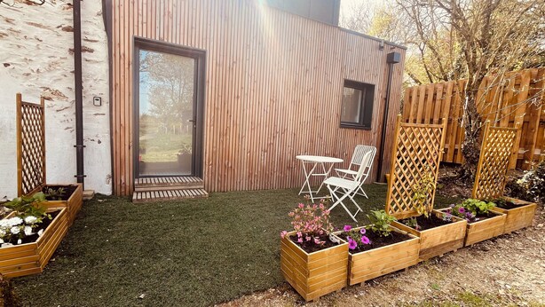 Un área de estar al aire libre moderna con una terraza de madera, una mesita y una silla.