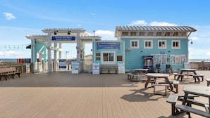 A beachside pier with picnic tables and a sign for Panama City Beach. - Stay at The Salty Palm! 2BR 1.5ba Sleeps 7 (Panama City Beach)