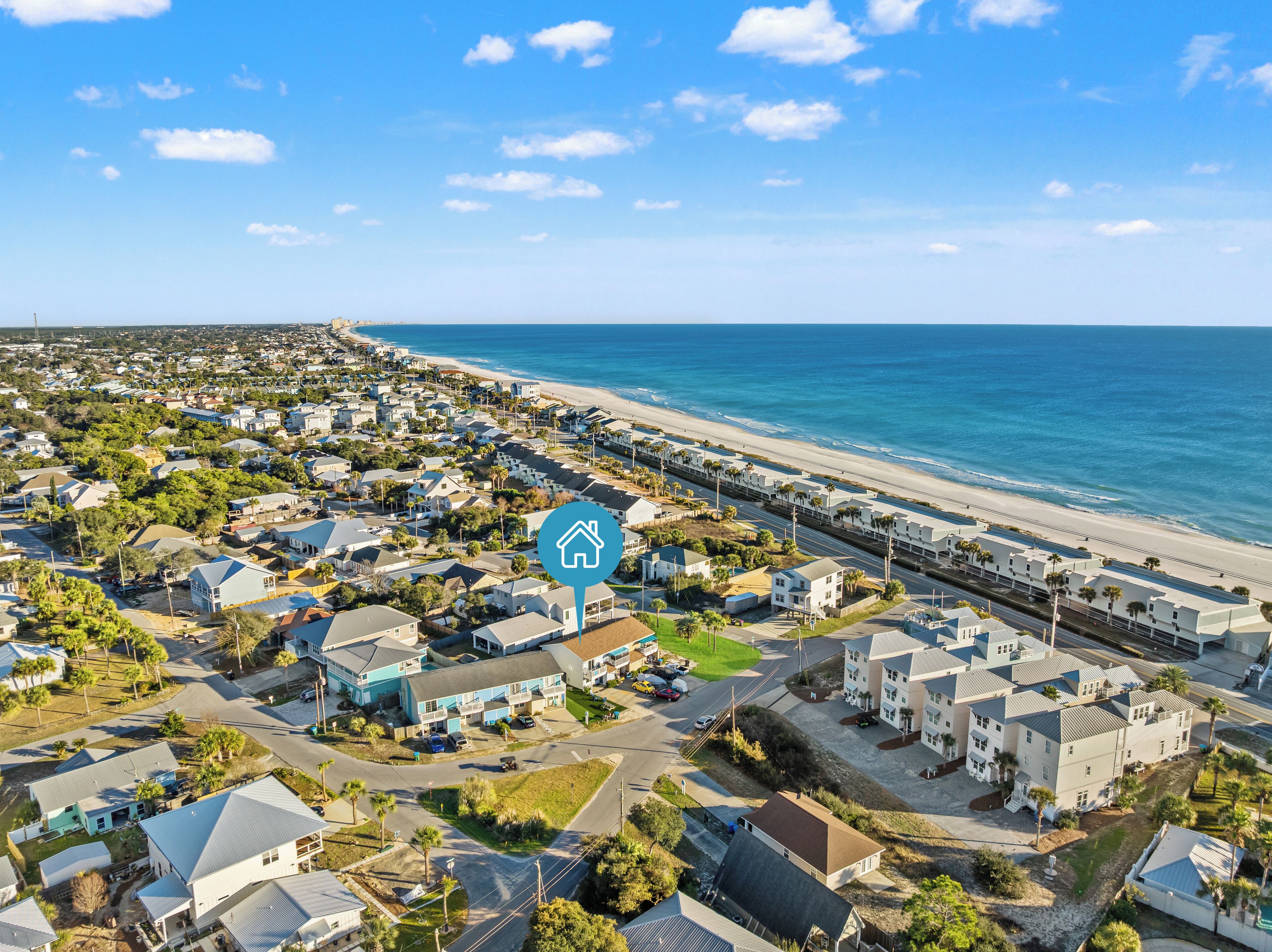 A coastal residential area with houses, a beach, and a clear sky.