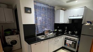 Une cuisine compacte équipée d’un lave-linge, d’une cuisinière et d’un réfrigérateur.