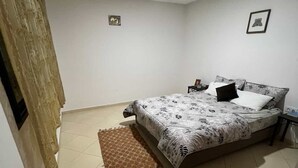 Une chambre à coucher avec un lit, une table de chevet, un tapis et un luminaire au plafond.