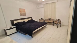 A bedroom with a bed, nightstand, and two chairs.