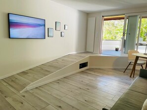 Ein modernes Wohnzimmer mit Holzboden, einem großen abstrakten Gemälde und einer Glastür zum Balkon.