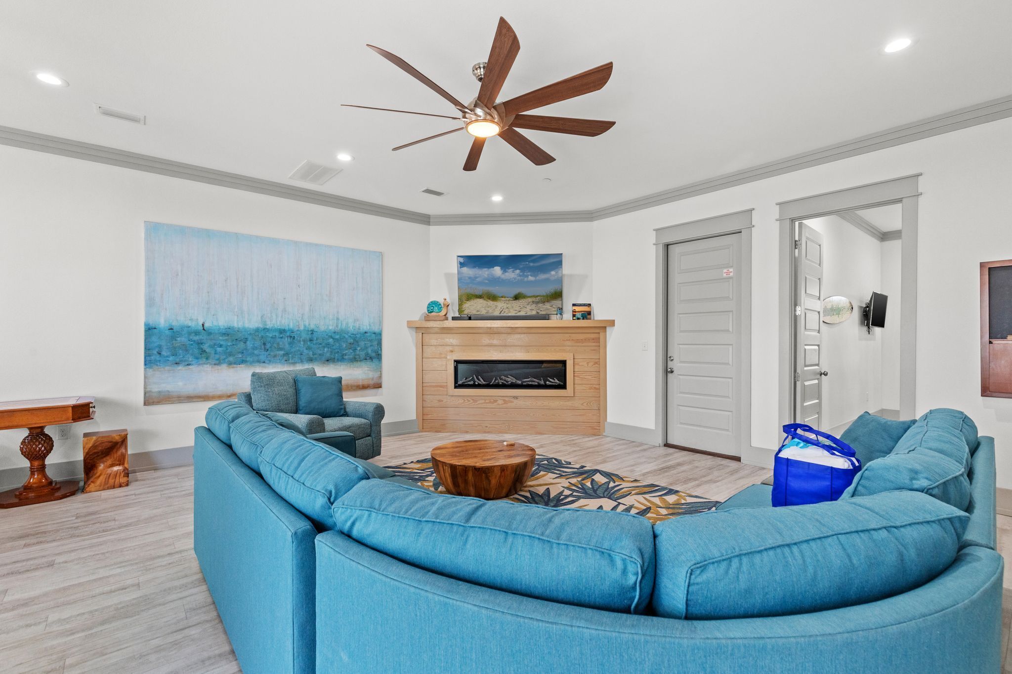 A modern living room with a blue sectional sofa, a wooden coffee table, and a fireplace.