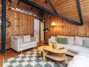 A cozy living room with wooden walls, a sofa, a coffee table, and a lamp. - 6 Person Holiday Home in Fjerritslev (Fjerritslev)