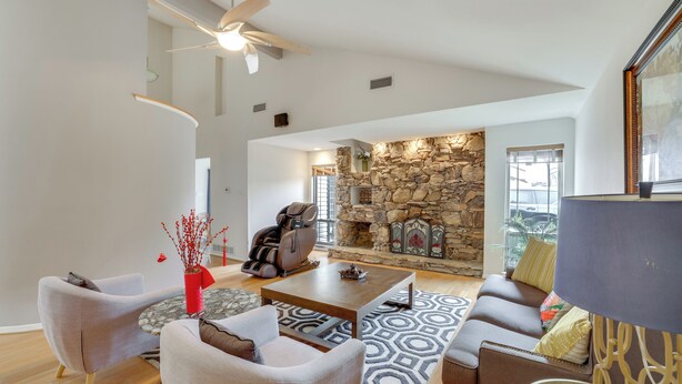 A spacious living room with a stone fireplace, a ceiling fan, and a large window. - 6 Mi to Dtwn Garland: Group Getaway w/ Pool Access (Garland)