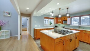 A modern kitchen with wooden cabinets, a large island, and pendant lighting. - 6 Mi to Dtwn Garland: Group Getaway w/ Pool Access (Garland)