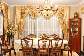 Une salle à manger avec une table ronde, six chaises et un lustre.