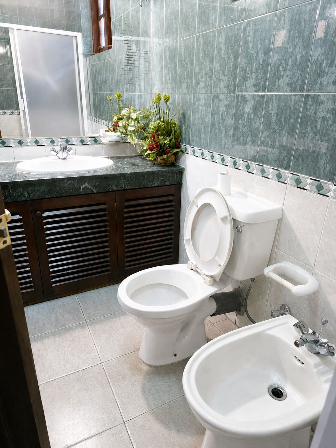 Et badeværelse med toilet, bidet og vask.