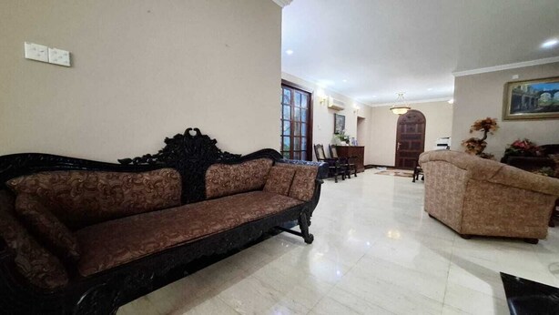 A spacious living room with a brown sofa, a beige sofa, and a dining area with chairs and a table.