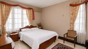 A bedroom with a bed, nightstands, a chair, a desk, and a potted plant. - Barnes Place Grand Residence Colombo 7 (Colombo)