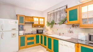 A kitchen with green and wooden cabinets, a white refrigerator, a microwave, and a sink.