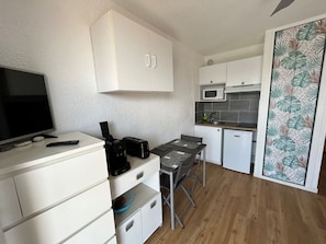 A compact kitchen with white cabinets, a microwave, a toaster, and a small dining table. - Studio for 2, 100m from beach (Argelès-sur-Mer)