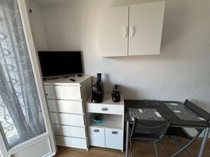 A small, compact room with a white wardrobe, a desk with a chair, a television, and a toaster. - Studio for 2, 100m from beach (Argelès-sur-Mer)