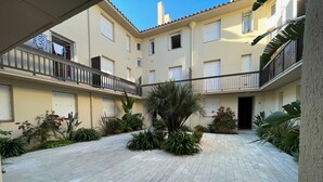 Um pátio com chão de azulejos, rodeado por edifícios com varandas e janelas.