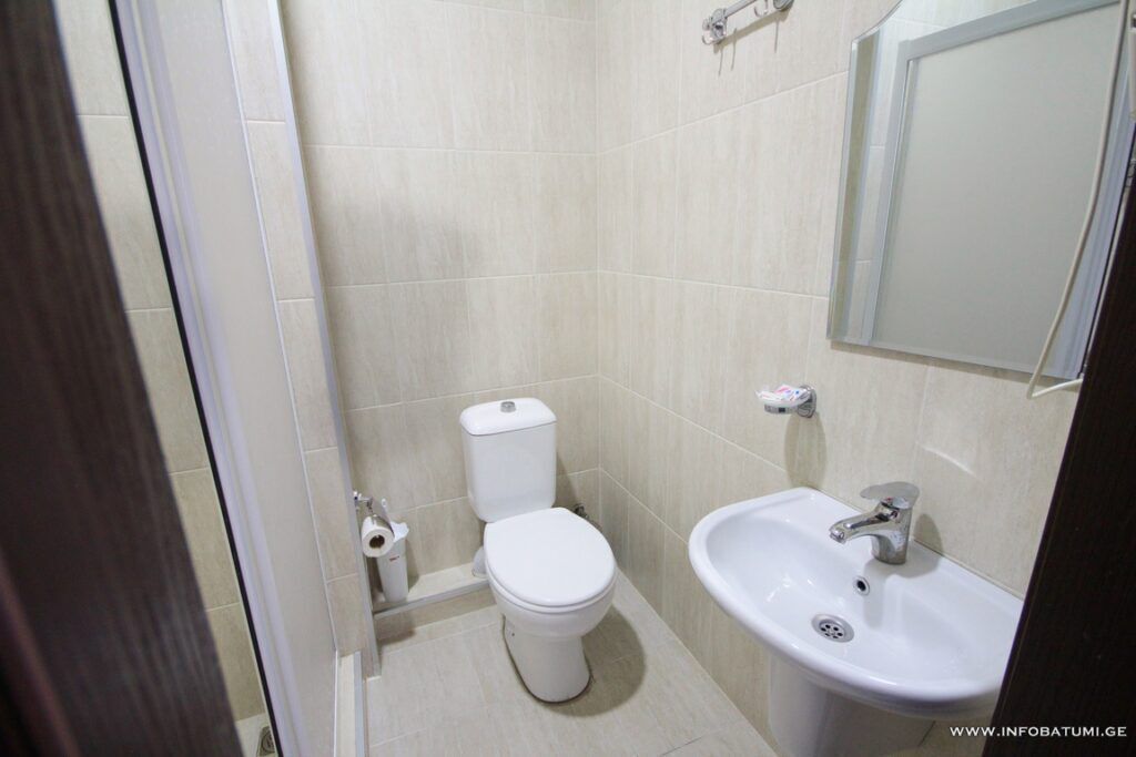 A small, clean bathroom with a toilet, sink, and mirror.