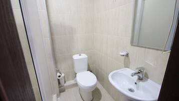 Un baño pequeño y limpio con inodoro, lavamanos y espejo.