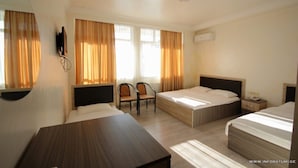 A hotel room with two beds, a desk, a chair, and a TV. - Hotel Temo (Batumi)