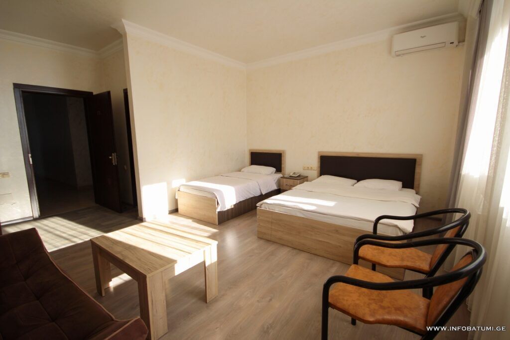 Una habitación de hotel con dos camas individuales, una mesa de madera, un sofá y dos sillas.