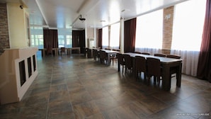 A spacious dining area with multiple tables and chairs, large windows with curtains, and a modern ceiling design. - Hotel Temo (Batumi)