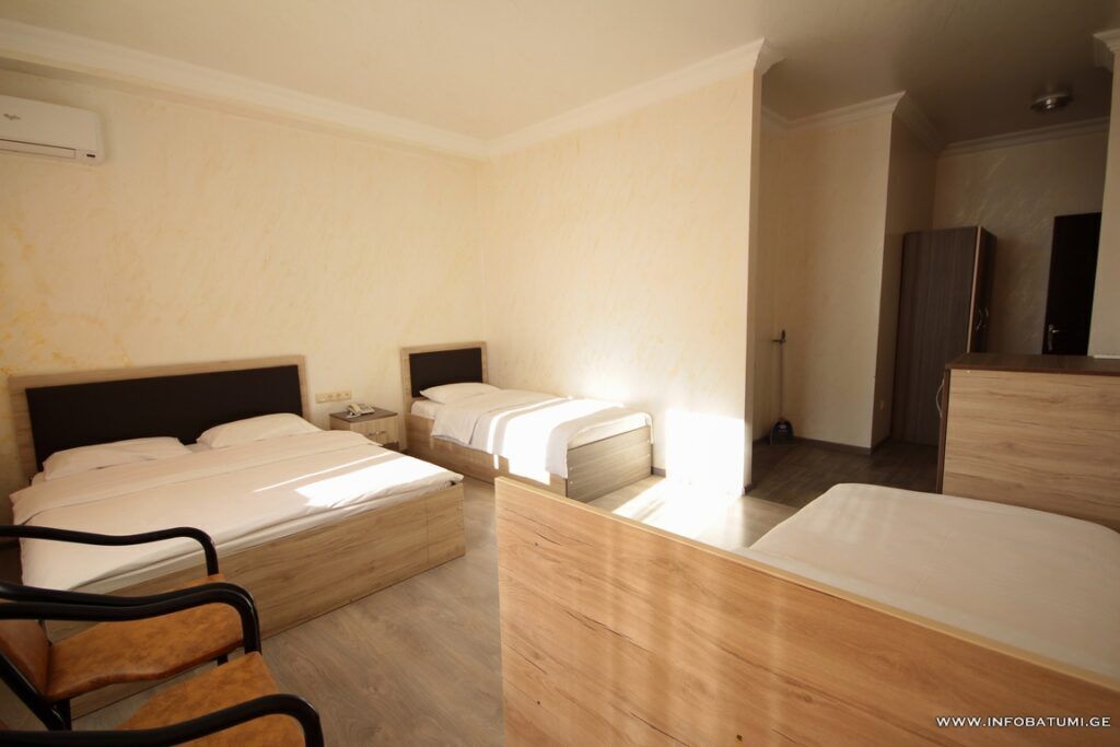 A bedroom with two beds, a chair, and a wardrobe.