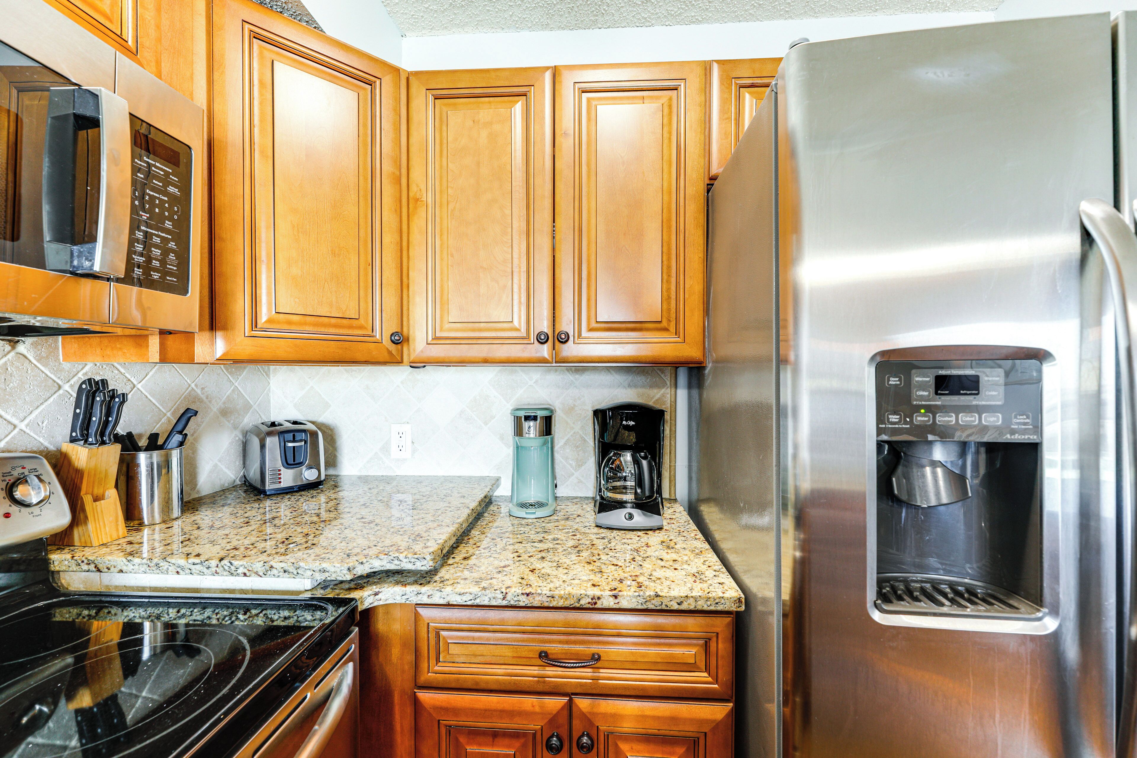 A kitchen with wooden cabinets, a stainless steel refrigerator, a coffee maker, and a microwave.