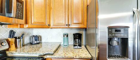 A kitchen with wooden cabinets, a stainless steel refrigerator, a coffee maker, and a microwave.
