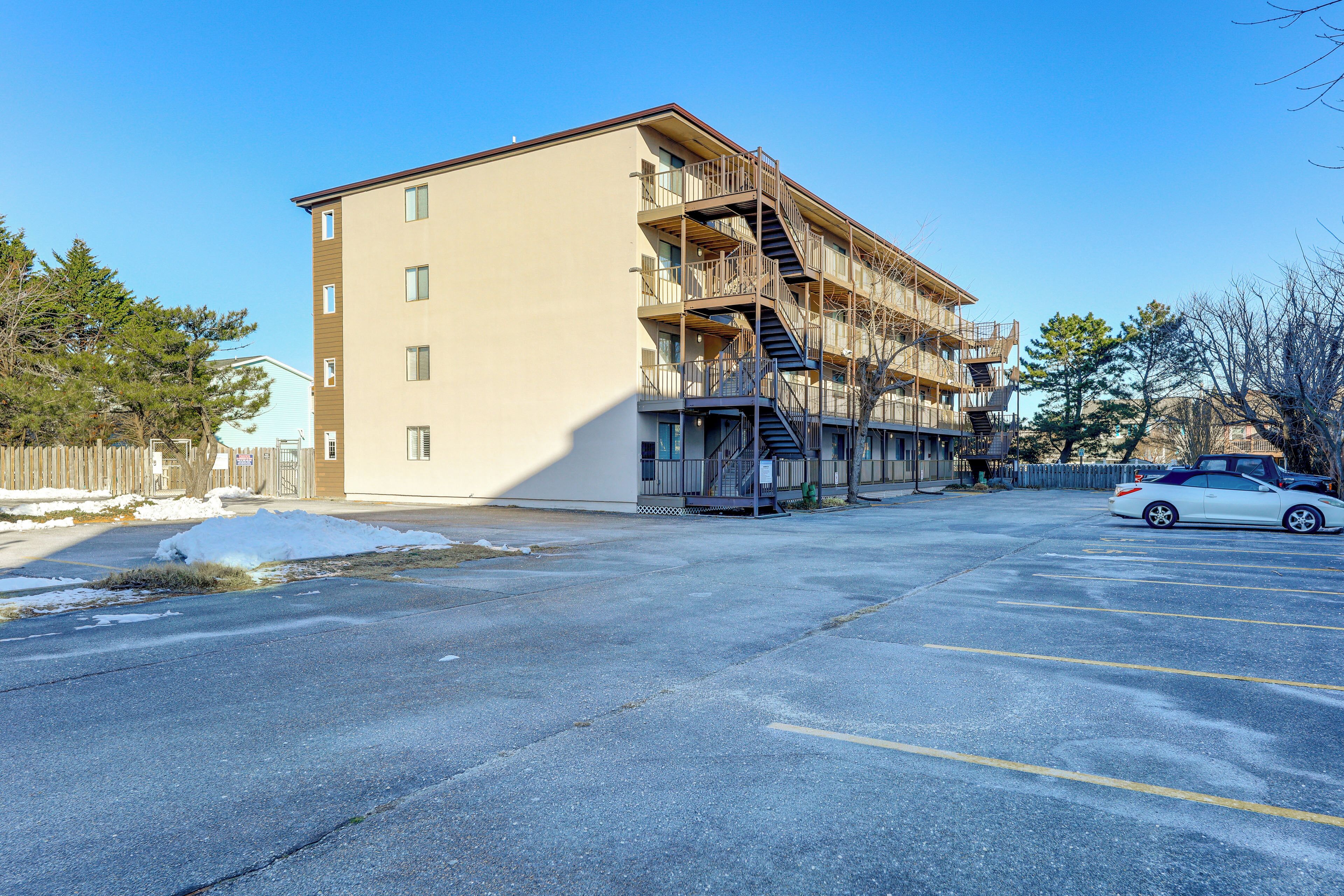 A multi-story building with a parking lot in front.