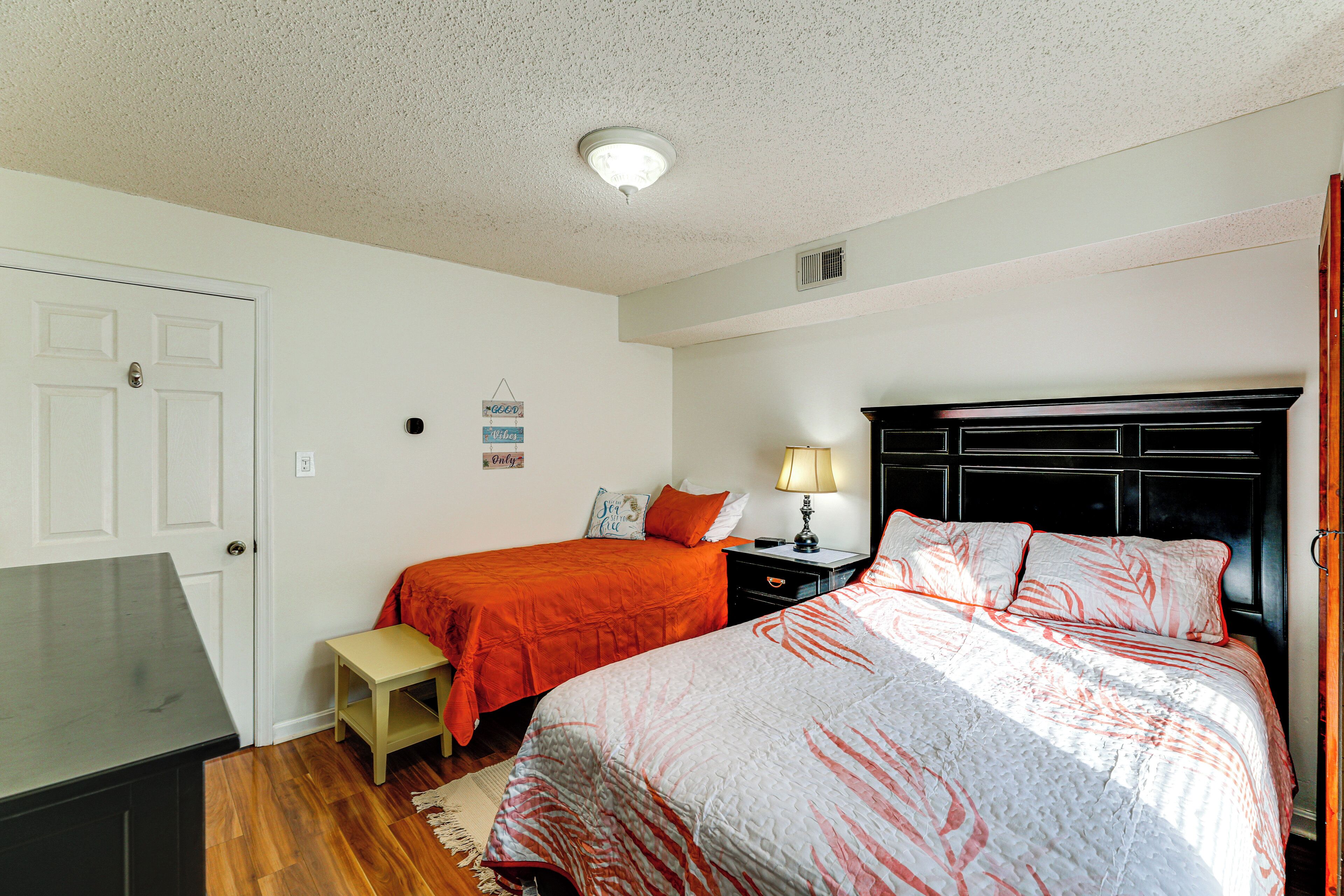 A bedroom with two beds, a desk, and a nightstand.