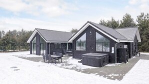 Een moderne cabin met een ruime patio, een hottub en een overdekte zithoek.