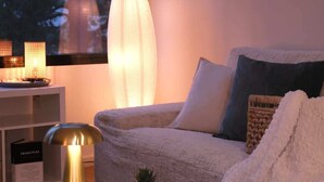Ett mysigt vardagsrum med en soffa, en lampa och ett litet bord med en växt.