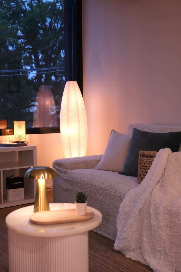A cozy living room with a sofa, a lamp, and a small table with a plant.
