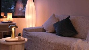 Ett mysigt vardagsrum med en soffa, en lampa och ett litet bord med en växt.