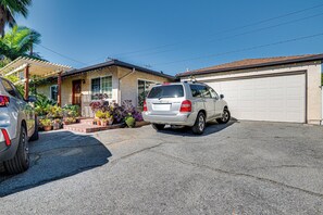 A residential driveway with a parked SUV and a car, a garage door, and a house with a covered porch and potted plants. - Solo 'cultural Retreat' in San Gabriel Valley! (San Gabriel)