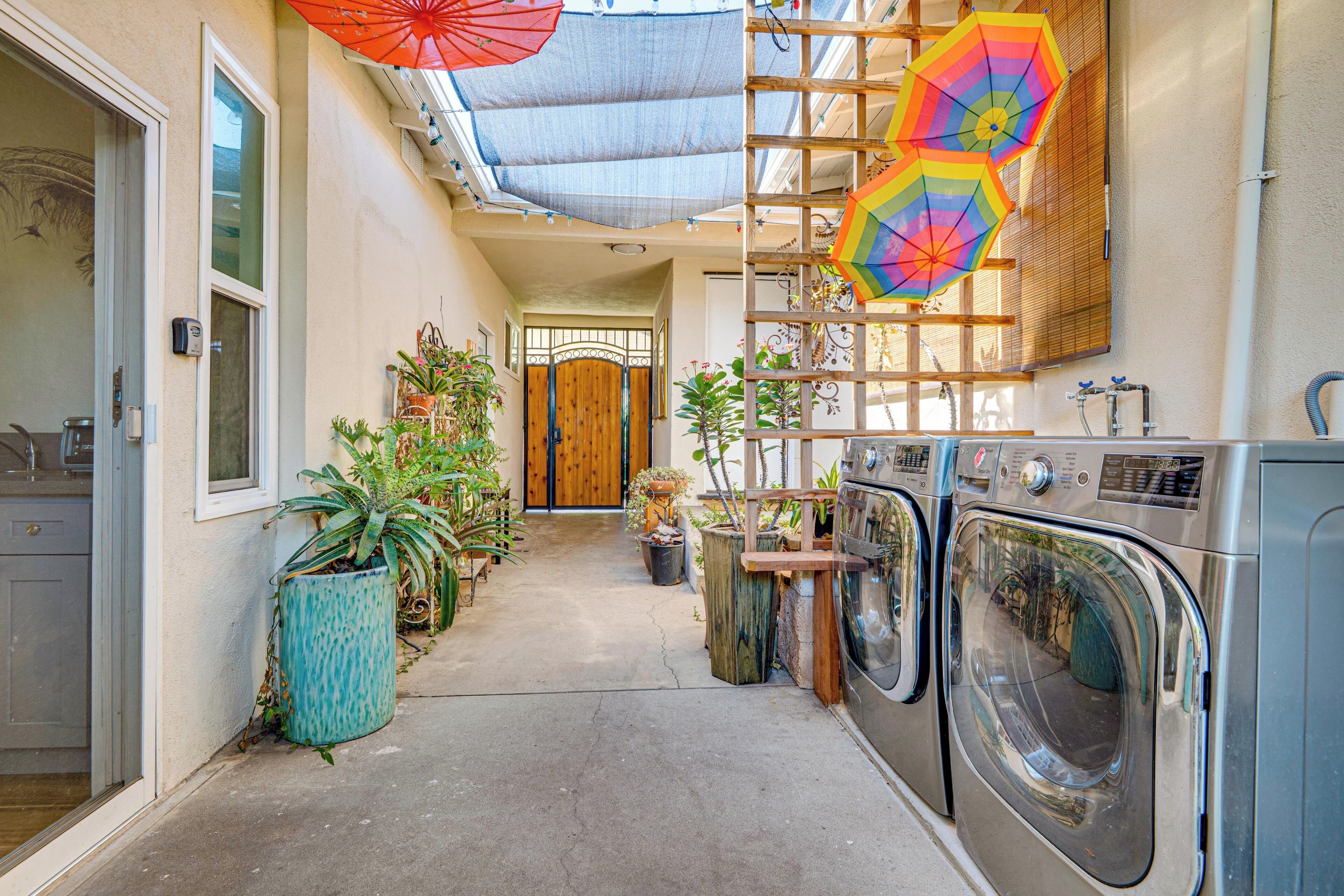 Een wasruimte met wasmachines, een houten deur en potplanten.