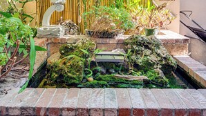 Un jardin japonais traditionnel avec un bassin à carpes koï, des bambous et des lanternes en pierre.