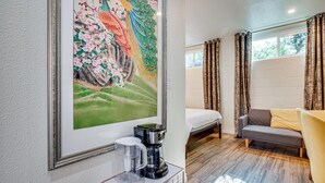 Une chambre d’hôtel avec un lit, un canapé, une machine à café et un tableau au mur.