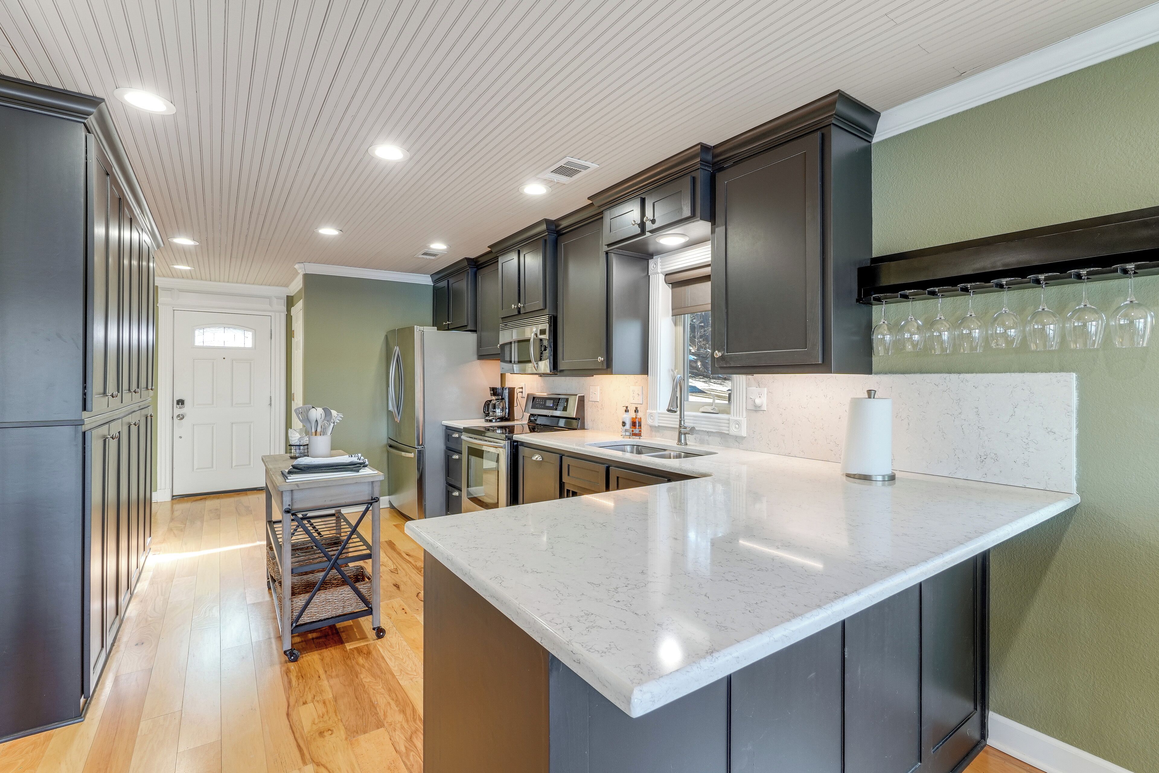 A modern kitchen with dark cabinets, a marble countertop, and a wine rack.