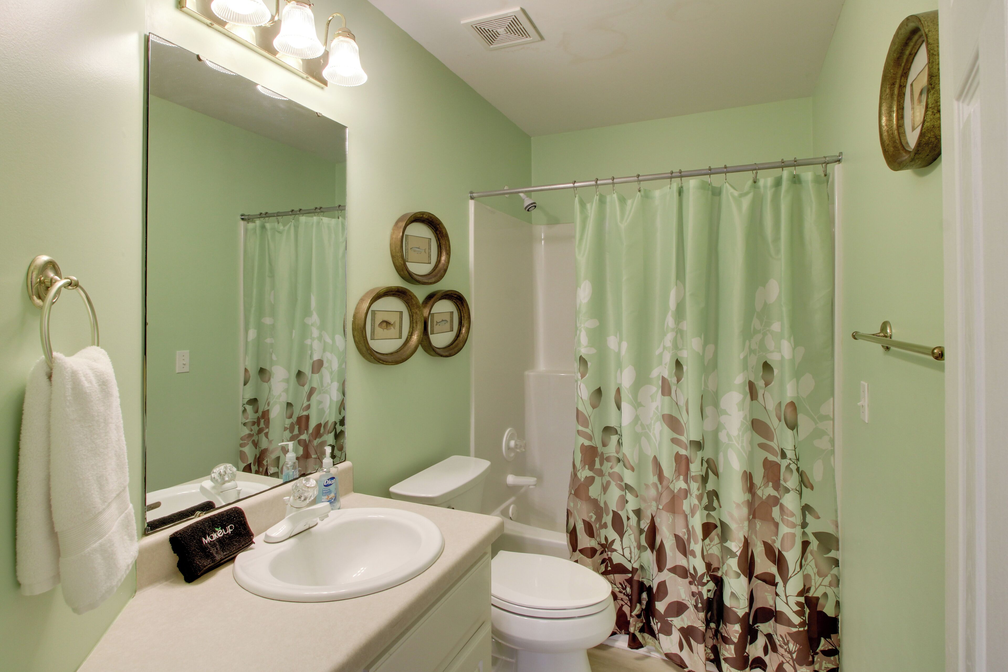 A bathroom with a sink, toilet, and shower curtain.