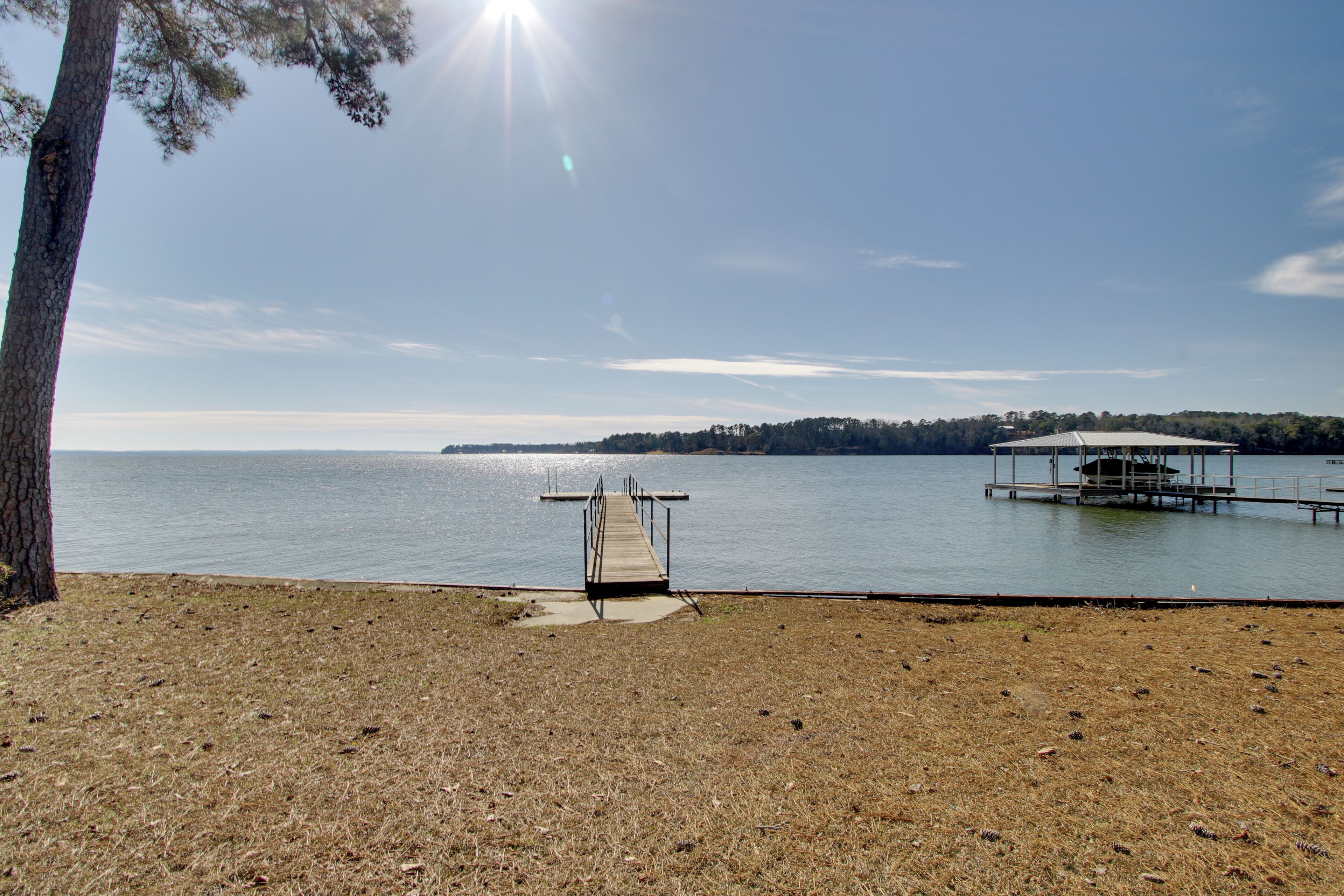 A lakeside view with a dock leading to a boat house.