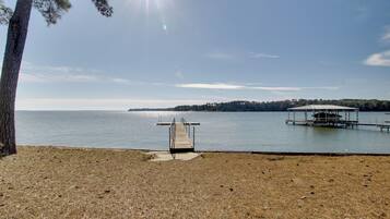 A lakeside view with a dock leading to a boat house.