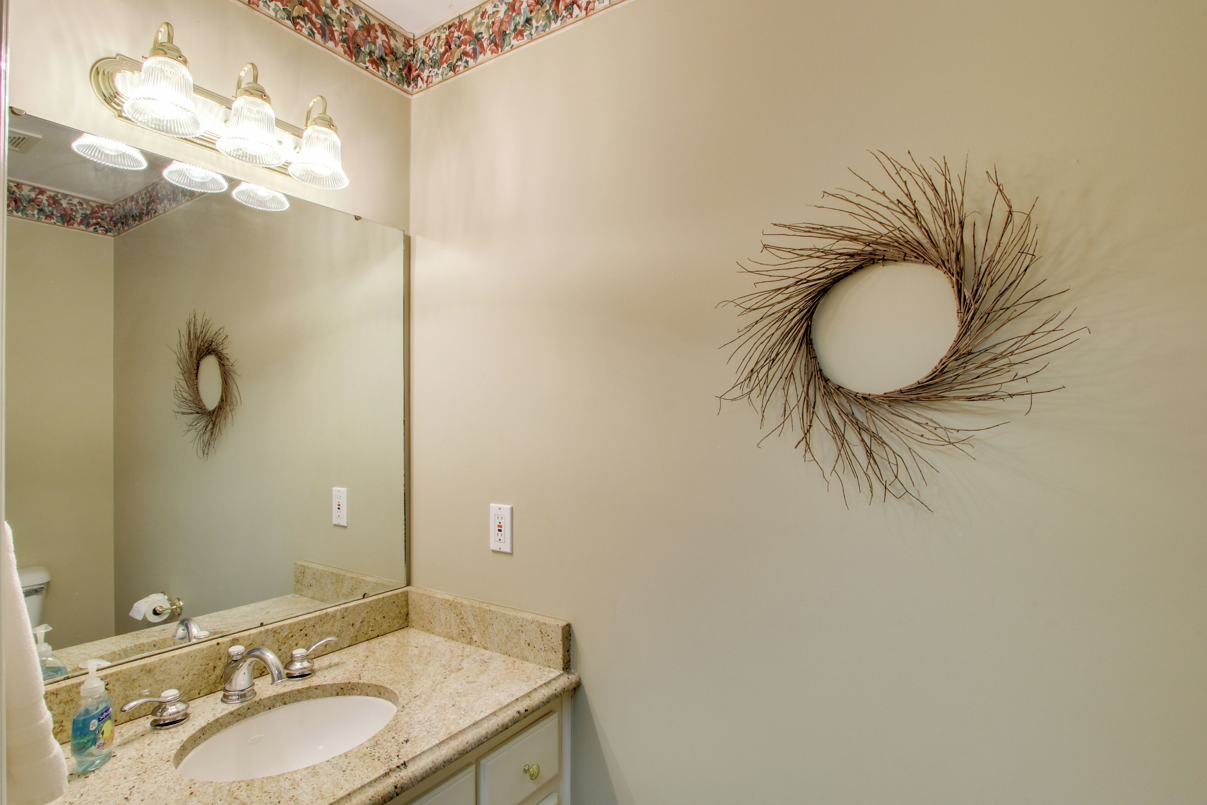 Un baño con lavamanos, espejo y decoración mural.