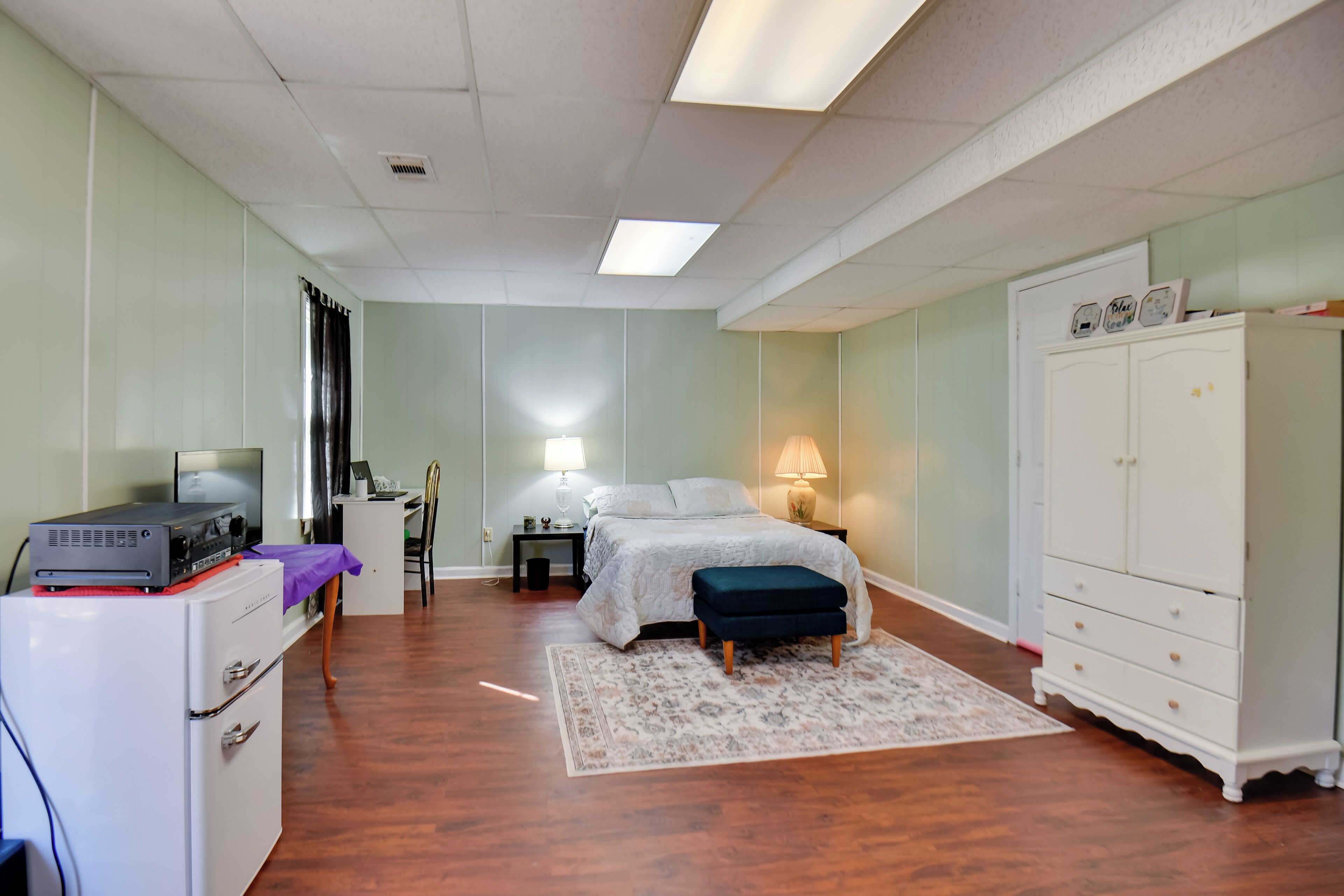 A bedroom with a bed, a desk, a wardrobe, and a television on a cabinet.