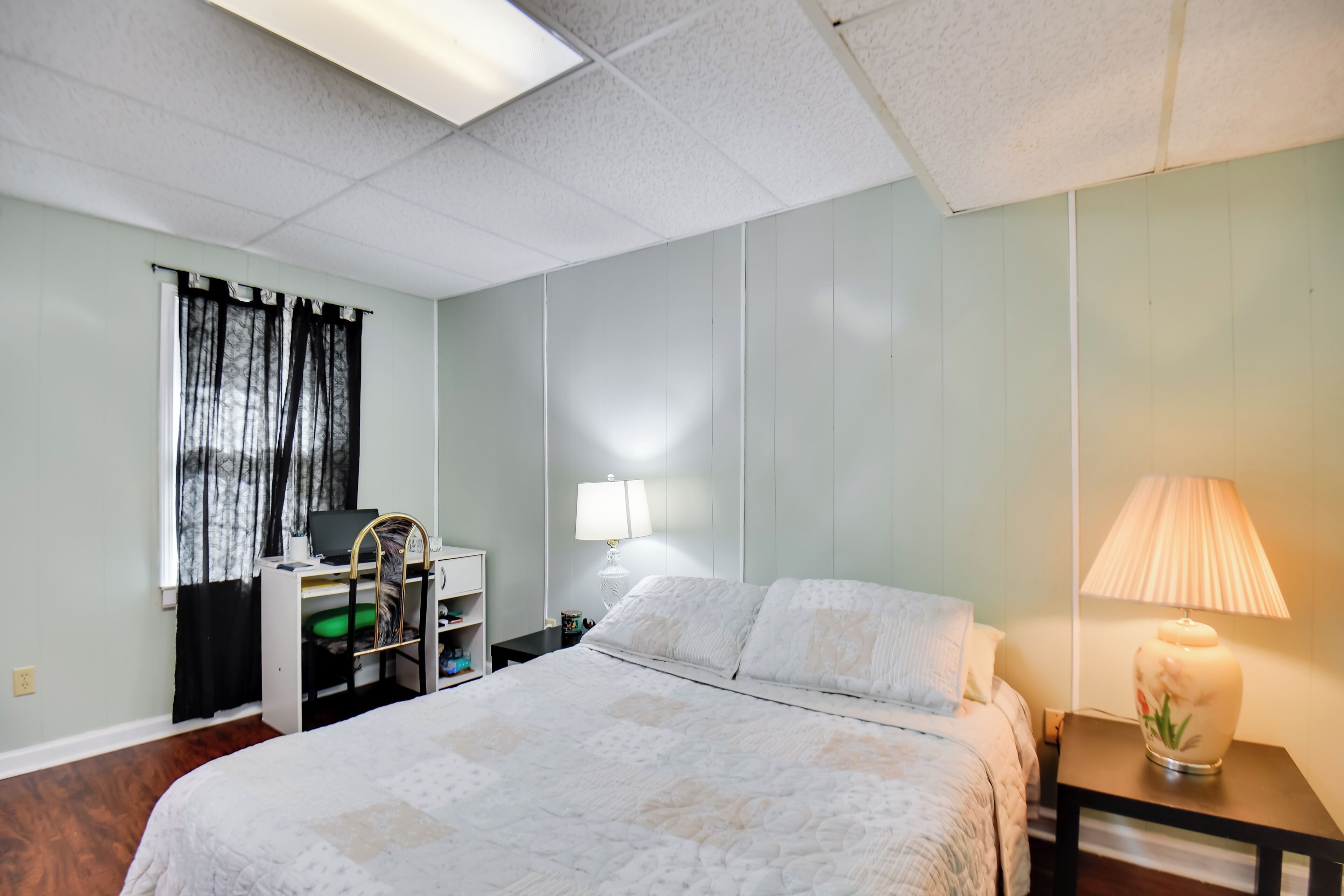 A neatly arranged hotel room with a bed, a desk, and a lamp.