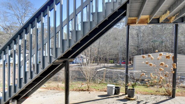 A metal staircase leading to a covered area with a view of a parking lot and trees in the background.